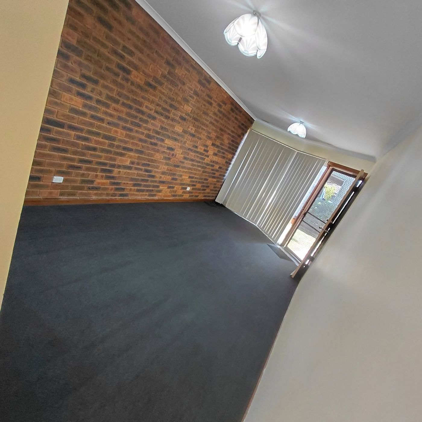 Clean dark blue carpet beside a brick feature wall